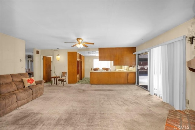 living area with light carpet and ceiling fan