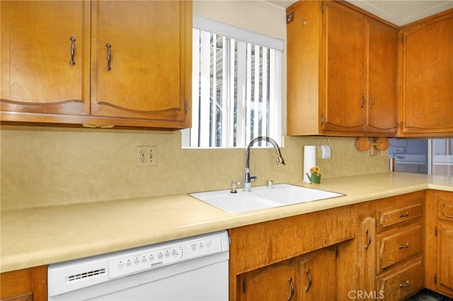 kitchen featuring light countertops, brown cabinetry, white dishwasher, and a sink