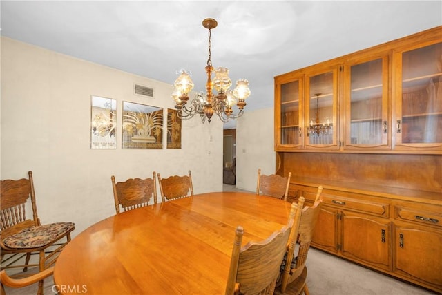 dining space with a chandelier, visible vents, and light carpet