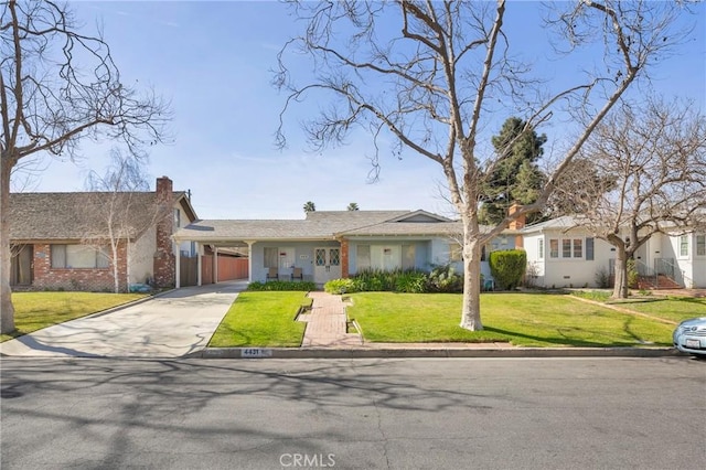 ranch-style house with a carport, concrete driveway, a chimney, and a front yard