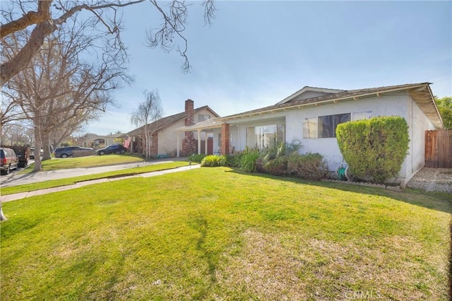 ranch-style house featuring stucco siding, fence, and a front yard