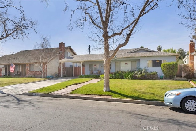 ranch-style home featuring fence, concrete driveway, stucco siding, a chimney, and a front yard