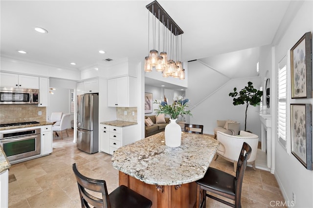 kitchen with backsplash, appliances with stainless steel finishes, stone tile floors, and light stone counters