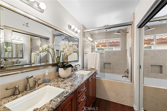 full bathroom featuring tiled shower / bath combo, a healthy amount of sunlight, wood finished floors, and a sink