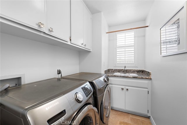 laundry area featuring stone finish floor, a wealth of natural light, washing machine and clothes dryer, and a sink