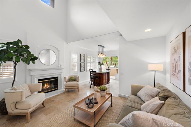 living area with baseboards, a glass covered fireplace, and recessed lighting