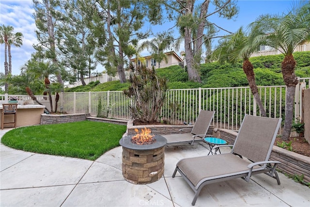 view of patio / terrace with a fenced backyard, exterior kitchen, and an outdoor fire pit