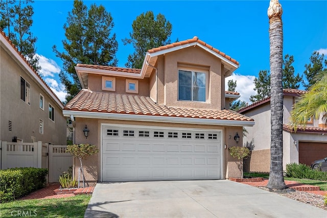 mediterranean / spanish home with a tile roof, concrete driveway, fence, a garage, and stucco siding