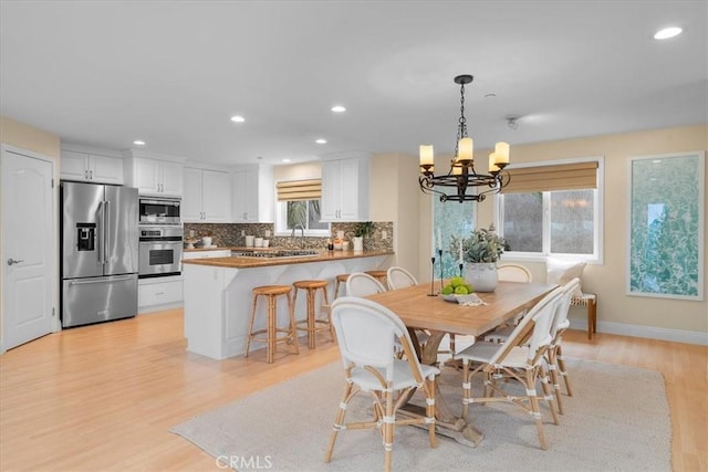 dining area with light wood-style flooring, recessed lighting, baseboards, and a chandelier