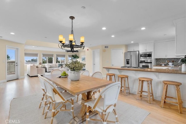 dining space featuring recessed lighting, light wood-type flooring, and a chandelier