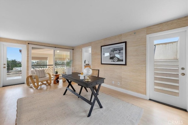 office area featuring wallpapered walls, baseboards, and wood finished floors