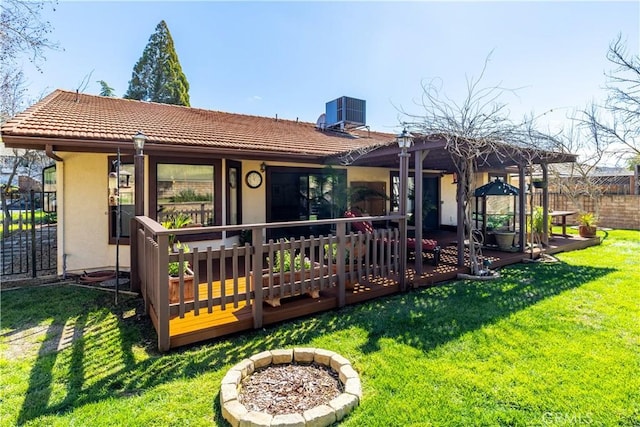 back of property with a yard, central air condition unit, fence, and stucco siding