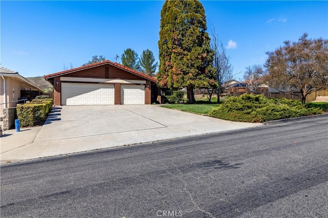 single story home with a garage, concrete driveway, and fence