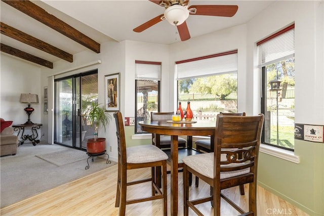 dining room featuring light wood finished floors, beamed ceiling, a ceiling fan, and baseboards