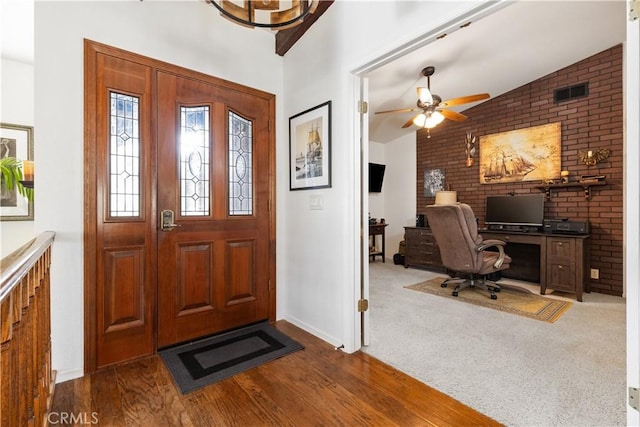 foyer entrance with carpet, visible vents, vaulted ceiling, and wood finished floors