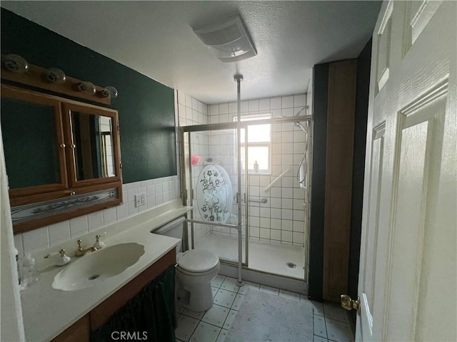 full bathroom featuring toilet, tile patterned flooring, a shower stall, and tile walls