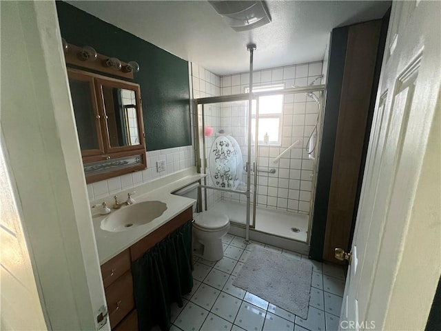 full bath featuring tile walls, toilet, a stall shower, vanity, and tile patterned flooring