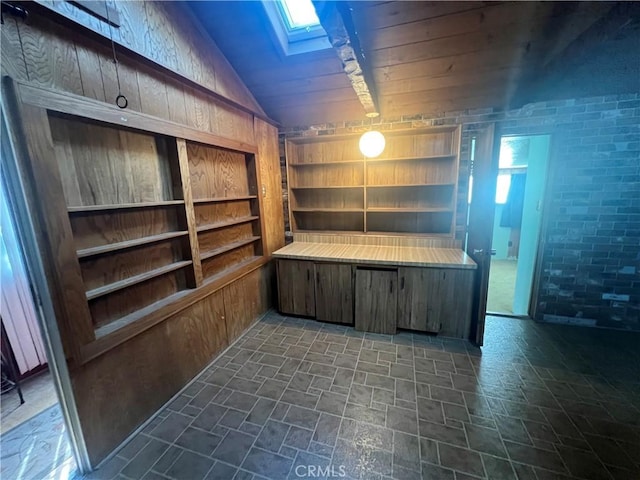 interior space featuring a wealth of natural light, vaulted ceiling with skylight, and brick wall