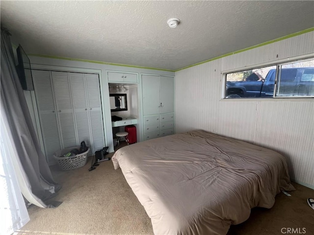 bedroom with a textured ceiling, carpet flooring, and multiple closets