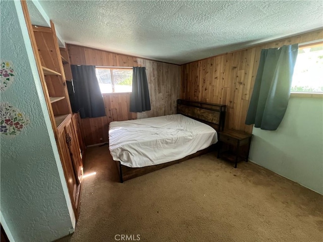 carpeted bedroom featuring a textured wall, wood walls, and a textured ceiling