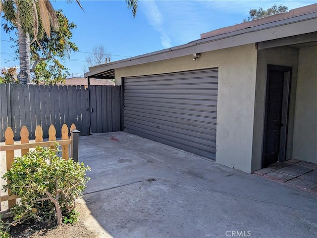 garage with fence and concrete driveway