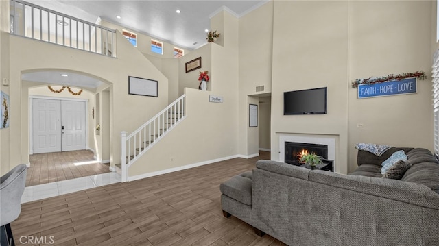 living area with visible vents, baseboards, a lit fireplace, stairway, and wood tiled floor