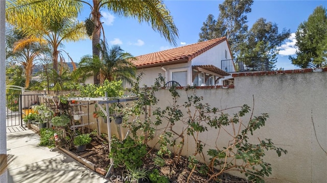 view of property exterior with a gate, fence, a tiled roof, and stucco siding