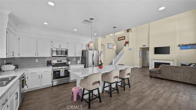 kitchen with visible vents, decorative backsplash, a breakfast bar area, stainless steel appliances, and white cabinetry