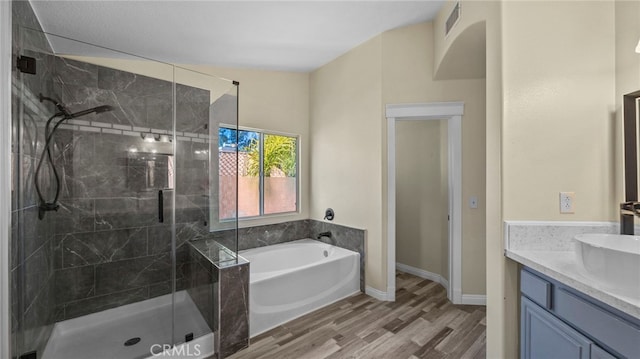 bathroom featuring a stall shower, visible vents, a bath, and wood finished floors