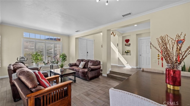 living area featuring crown molding, visible vents, wood finished floors, baseboards, and stairs