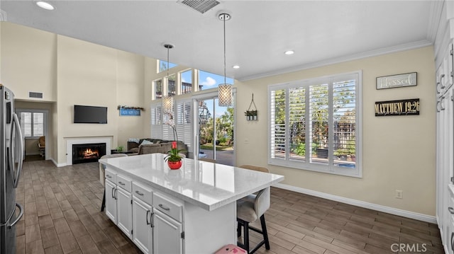 kitchen with a warm lit fireplace, visible vents, white cabinets, freestanding refrigerator, and wood finish floors