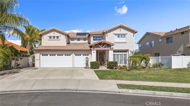 traditional home with a garage, concrete driveway, fence, roof mounted solar panels, and a front yard