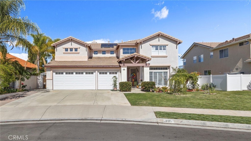723 Rembrandt Cir, Corona, CA 92882 - traditional-style house featuring roof mounted solar panels, fence, a front lawn, stucco siding, and an attached garage