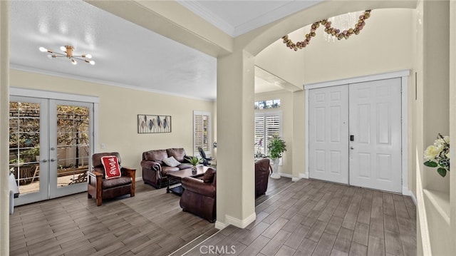 foyer featuring crown molding, french doors, a notable chandelier, and wood finished floors