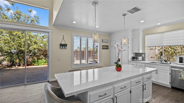 kitchen with visible vents, ornamental molding, wood finished floors, white cabinetry, and stainless steel dishwasher