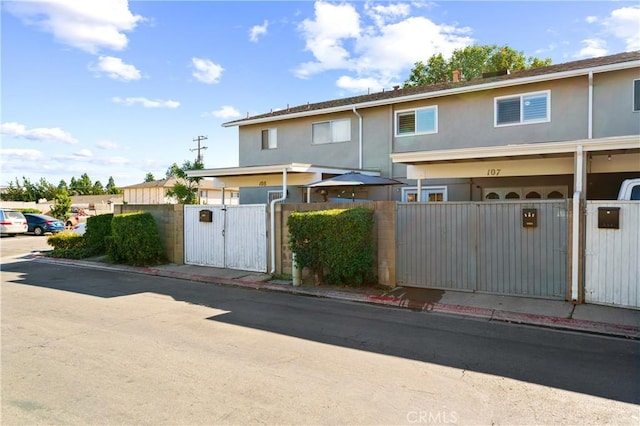 townhome / multi-family property featuring a fenced front yard, a gate, and stucco siding