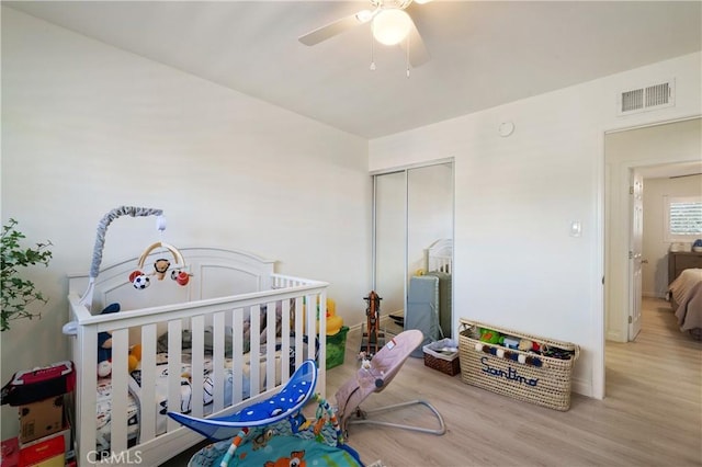 bedroom with ceiling fan, a closet, visible vents, and wood finished floors