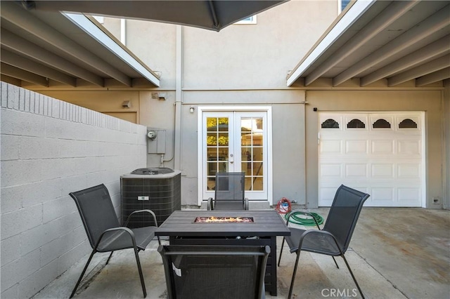 view of patio / terrace with french doors, central air condition unit, concrete driveway, an outdoor fire pit, and fence