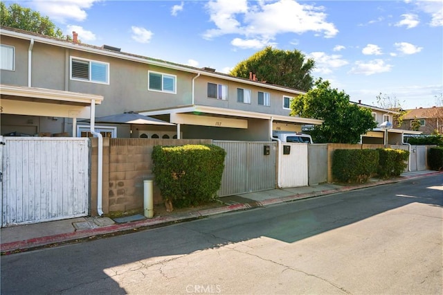 multi unit property with a fenced front yard, a gate, and stucco siding