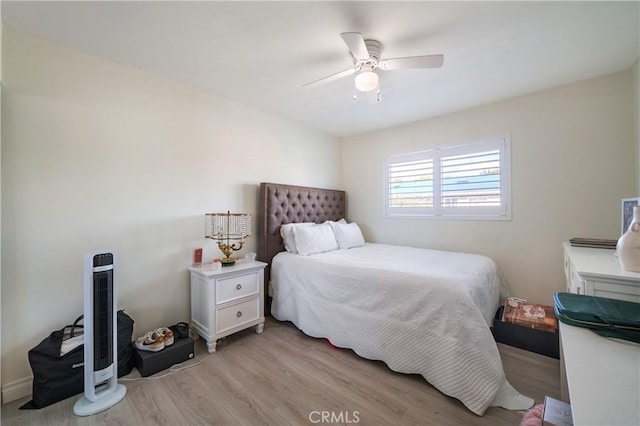 bedroom featuring heating unit, light wood-style flooring, and a ceiling fan