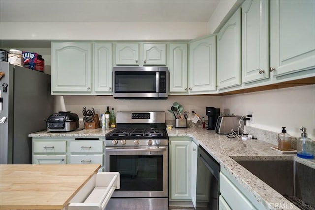 kitchen with stainless steel appliances, a sink, and light stone countertops