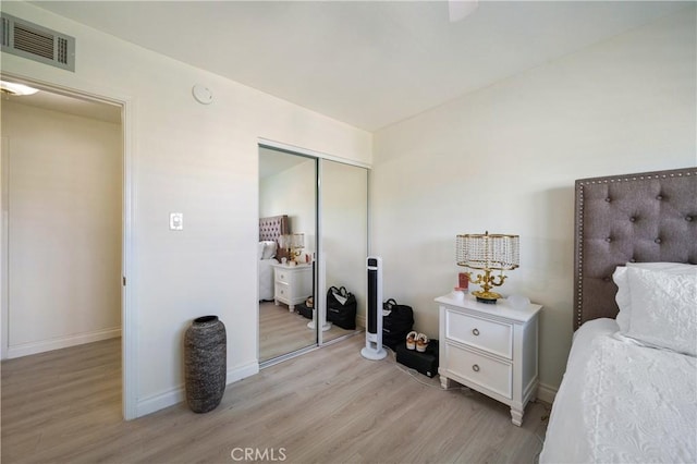 bedroom featuring a closet, visible vents, light wood-style flooring, and baseboards