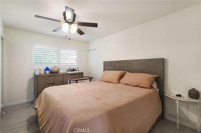 bedroom featuring ceiling fan, light wood-style floors, a closet, and baseboards