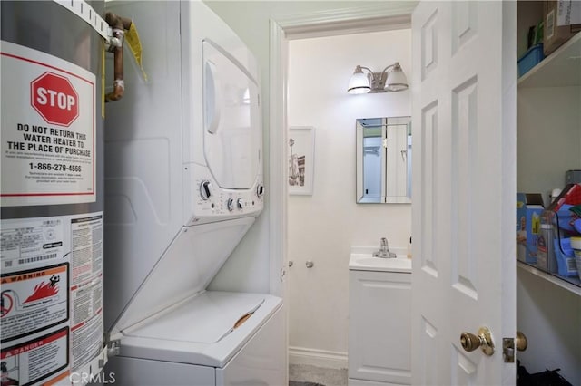 laundry room with gas water heater, laundry area, a sink, baseboards, and stacked washing maching and dryer