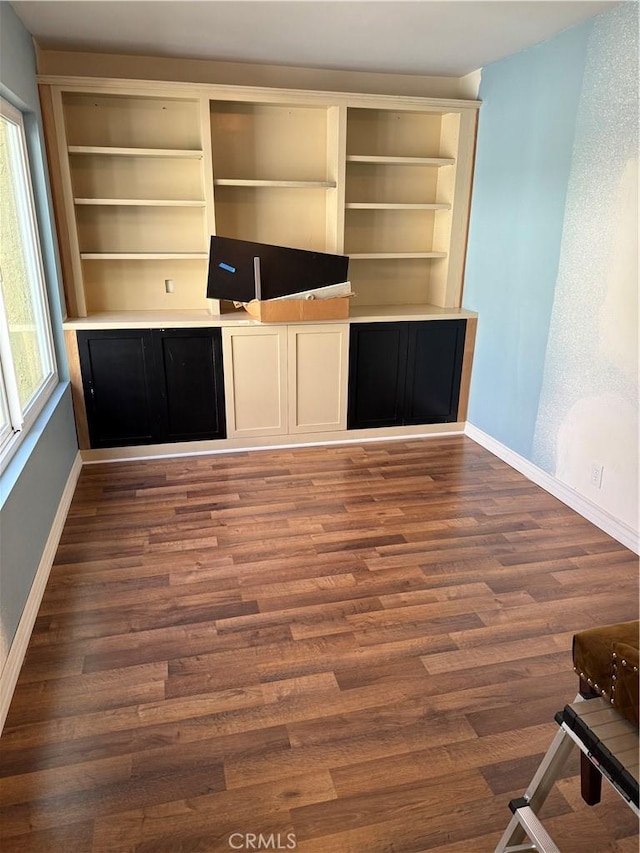 unfurnished living room featuring dark wood finished floors and baseboards