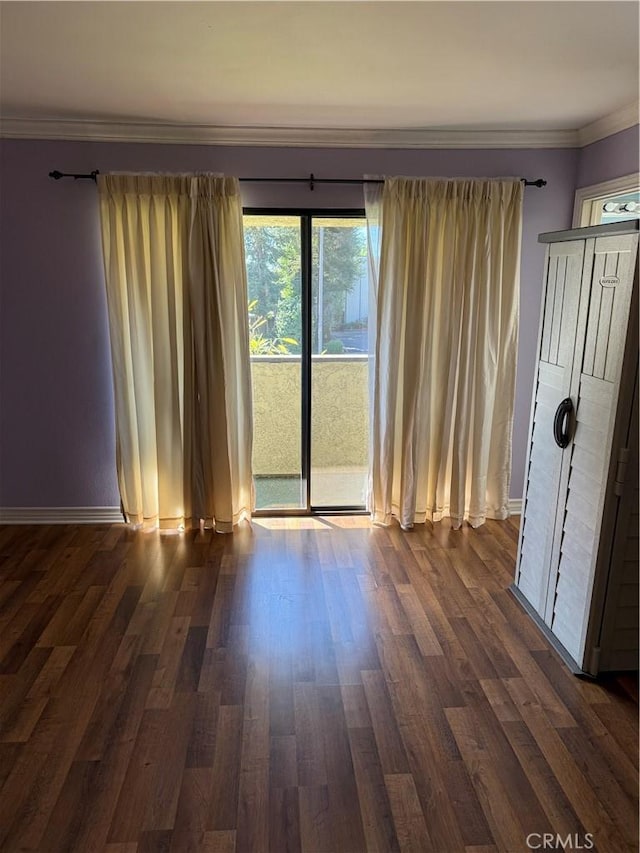 interior space with baseboards, dark wood-style flooring, and crown molding