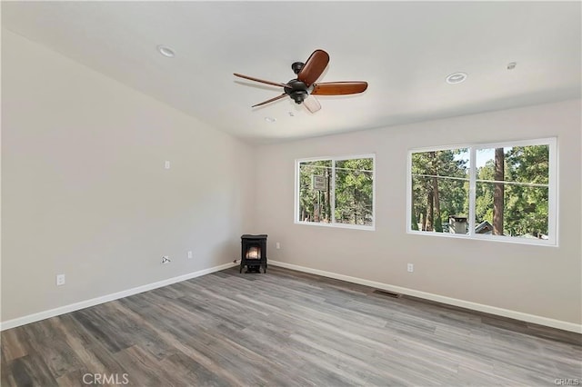 23511 Lake Dr, Crestline, CA 92325 - spare room featuring a wood stove, baseboards, ceiling fan, wood finished floors, and recessed lighting
