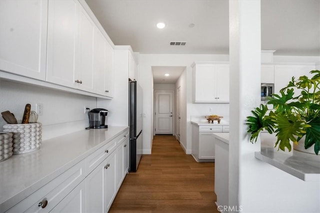 kitchen featuring visible vents, dark wood-type flooring, freestanding refrigerator, light countertops, and white cabinetry