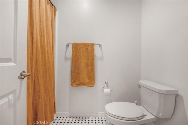 bathroom featuring curtained shower, baseboards, and toilet