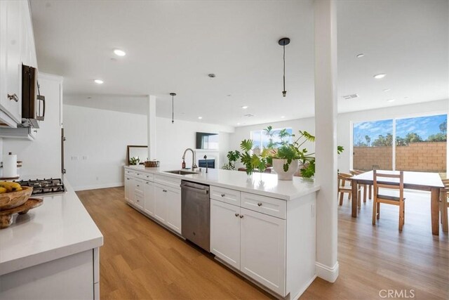 kitchen with light wood finished floors, stainless steel appliances, a sink, and light countertops